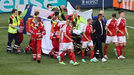 Les joueurs danois rassemblés autour de la civière qui évacue Christian Eriksen à Copenhague, le 12 juin 2021. (WOLFGANG RATTAY / AFP)