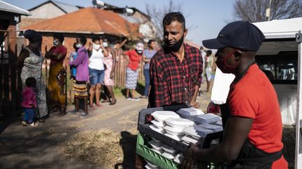 Des bénévoles distribuent de la&nbsp;nourriture dans un quartier de Johannesburg (Afrique du Sud) le 12 mai 2020, pendant le confinement lié à l'épidémie de coronavirus. (WIKUS DE WET / AFP)