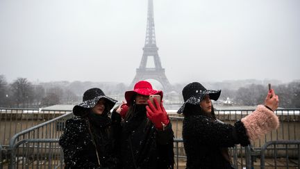 Des touristes se prennent en photo devant la tour Eiffel, à Paris, le 5 février 2018. (LIONEL BONAVENTURE / AFP)