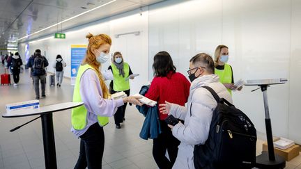 Une employée du service de santé municipal néerlandais distribue des autotests Covid-19 gratuits aux voyageurs arrivant de Chine, à l'aéroport d'Amsterdam, le 4 janvier 2023. (ROBIN VAN LONKHUIJSEN / ANP)