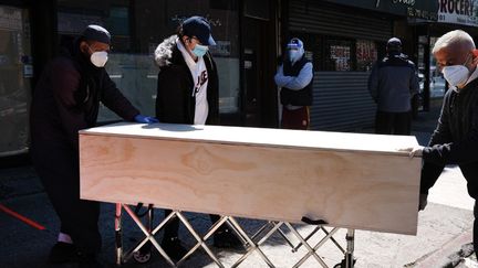 Trois hommes déplacent le cercueil d'une victime du coronavirus, le 9 mai 2020 à New York (Etats-Unis). (SPENCER PLATT / GETTY IMAGES NORTH AMERICA / AFP)