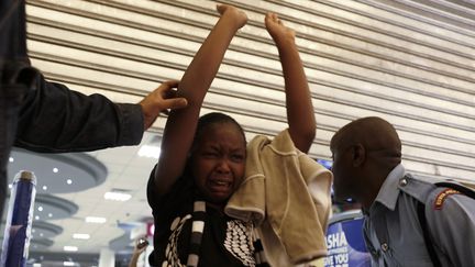 Un officier de police aide une jeune femme &agrave; sortir du centre commercial &agrave; Nairobi (Kenya) lors d'une attaque terroriste, le 21 septembre 2013. ( REUTERS)