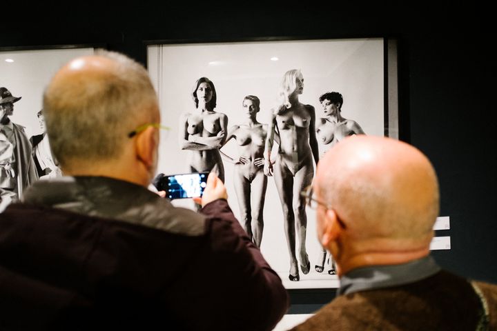 Des visteurs devant la célèbre série de photos "Naked and Dressed" d'Helmut Newton lors d'une exposition à Naples en 2017. (ELIANO IMPERATO / CONTROLUCE)