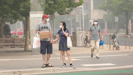 Des passants se protègent le visage avec des masques à Canberra. Dimanche 5 janvier, la capitale fédérale australienne est passée en tête des villes les plus polluées au monde,&nbsp;conséquence&nbsp;des incendies&nbsp;qui ravagent le sud du pays. (CHU CHEN / XINHUA)