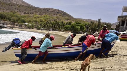 Des pêcheurs ramènent leur bateau sur la plage de Tarrafal, au nord de l'île de Santiago, au Cap-Vert, le 14 avril 2021. (SEYLLOU / AFP)