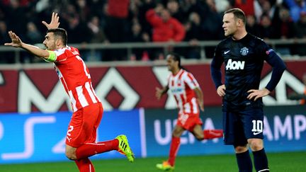 Giannis Maniatis célèbre le but de l'Olympiakos, devant un Wayne Rooney dépité (YANNIS KOLESIDIS / AFP)