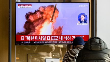 Des habitants de Séoul (Corée du Sud) regardent la télévision qui rapporte le nouveau tir d'un missile nord-coréen, dans une station de métro, le 18 novembre 2022. (ANTHONY WALLACE / AFP)