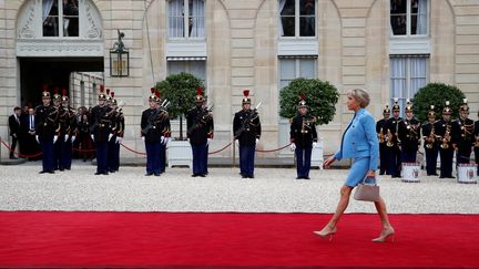 Vêtue d'un tailleur bleu dessiné par Nicolas Gesquière pour Louis Vuitton, la Première Dame, Brigitte Macron, fait son entrée dans la cour de l'Elysée, avant son mari. (CHRISTIAN HARTMANN / REUTERS)