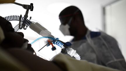 Un soignant près d'un malade sous assistance respiratoire infecté par le Covid-19, à l'hôpital Ambroise Paré à Boulogne Billancourt, le 8 mars 2021. (ALAIN JOCARD / AFP)