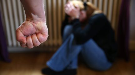 Une femme prostrée se protége des coups d'un homme. Photo d'illustration. (MAXPPP)