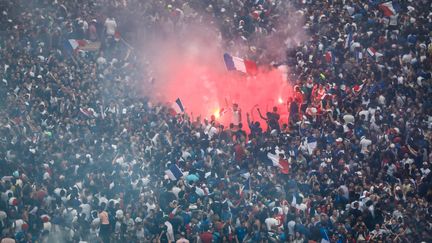 Au pied de l'Arc de Triomphe, des supporters dansent à la lumière des fumigènes. (LUDOVIC MARIN / AFP)