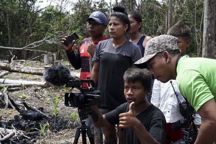 Un jeune Tikuna s'essaye à la caméra sous la supervision&nbsp;d'un Matis à&nbsp;San Martin de Amacayacu&nbsp;en Colombie, le 14 octobre 2022. (LIONEL ROSSINI / AFP)