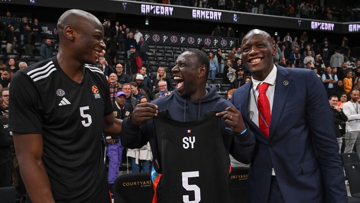 L'acteur français Omar Sy reçoit le maillot de Bandja Sy, joueur du Paris Basketball, sous les yeux du directeur sportif Amara Sy, le 1er novembre 2024, à l'Adidas Arena. (JULIEN MATTIA / EPA)