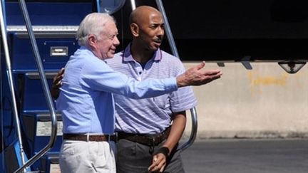 Jimmy Carter et Aijalon Mahli Gomes descendent de l'avion à Boston le 28 août 2010 (Getty)