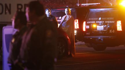 Une jeune femme enveloppée dans une couverture, devant le Borderline Bar, à Thousand Oaks (Californie, Etats-Unis), où un homme à ouvert le feu, le 7 novembre 2018. (MAXPPP)