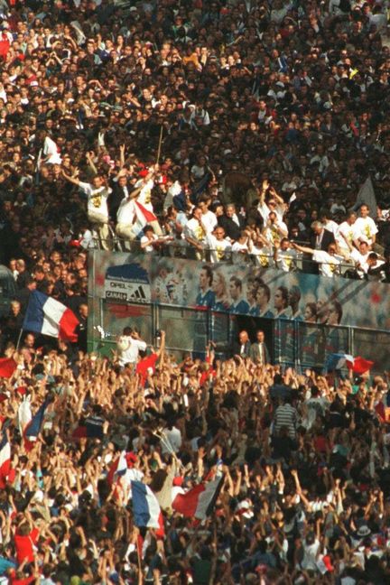 Le bus de l'équipe de France de football, toute fraîche championne du monde, se fraye un chemin dans la foule massée sur les Champs-Elysées, le 13 juillet 1998. (GAEL CORNIER/AP/SIPA / AP)