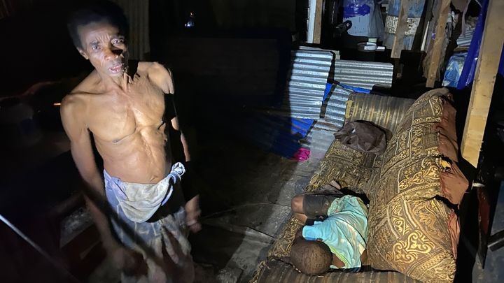 Ce père de famille, et son fils allongé sur le canapé, tentent de trouver de quoi se nourir, près d'une semaine après le passage de l'ouragan Chido à Mayotte. (BORIS LOUMAGNE / FRANCEINFO / RADIO FRANCE)