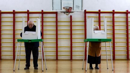 Des personnes dans un bureau de votes, à Tbilissi, en Géorgie, à l'occasion des élections législatives, le 26 octobre 2024. (GIORGI ARJEVANIDZE / AFP)