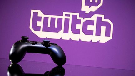 Une manette devant le logo de Twitch, le 15 juin 2021, à Toulouse. (LIONEL BONAVENTURE / AFP)