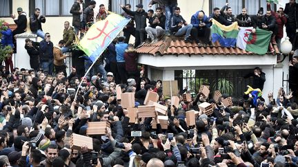 Des manifestants brandissent le drapeau berbère et des briques pour dire non à la présidentielle, à Tizi Ouzou, le 8 décembre 2019. (RYAD KRAMDI / AFP)