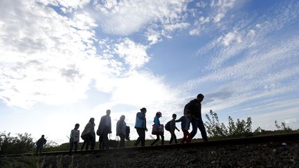 Des migrants marchent le long d'une voie ferr&eacute;e, le 7 septembre 2015, &agrave; Roszke (Hongrie). (LASZLO BALOGH / REUTERS)