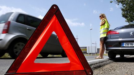 Un triangle signalant un véhicule en panne sur la route (illustration). (PATRICK BERNARD / AFP)