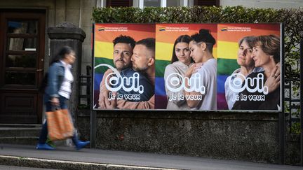 Une femme passe devant une affiche électorale "Oui je le veux" à quelques jours d'un vote sur le mariage pour tous en Suisse.&nbsp;Lausanne, 22 septembre 2021 (FABRICE COFFRINI / AFP)