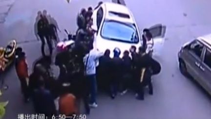 Capture d'&eacute;carn montrant les bons samaritains qui soul&egrave;vent la voiture pour lib&eacute;rer une&nbsp;femme qui se trouve en-dessous, dans&nbsp;la province du Zhejiang (Chine) (STERLIN TV / YOUTUBE)