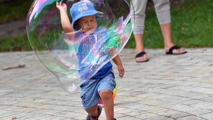 Un jeune gar&ccedil;on joue avec une bulle de savon g&eacute;ante dans un parc de Kiev (Ukraine), le 5 juillet 2013. (SERGEI SUPINSKY / AFP)