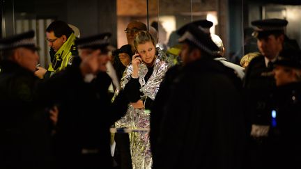 Une jeune spectatrice, prise en charge par les secours, t&eacute;l&eacute;phone &agrave; la sortie de l'Apollo Theatre, dont une partie du toit s'est effondr&eacute;, le 19 d&eacute;cembre 2013, &agrave; Londres (Royaume-Uni). (LEON NEAL / AFP)