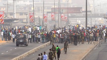 Des manifestants rassembl&eacute;s pour protester contre la hausse du prix de l'essence, sous la surveillance de militaires arm&eacute;s, le 16 janvier 2012 &agrave; Lagos (Nigeria). (PIUS UTOMI EKPEI / AFP)