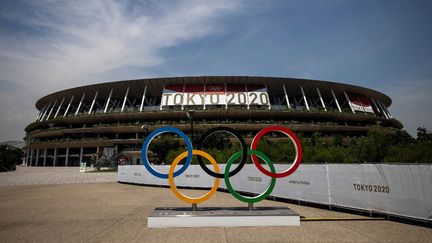 Les anneaux olympiques devant le stade des Jeux de Tokyo, le 20 juillet 2021. (BEHROUZ MEHRI / AFP)