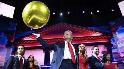 Un ballon doré repose au-dessus de la main de Donald Trump, sur la scène de la convention républicaine, le 18 juillet 2024. Derrière lui, on aperçoit son épouse, Melania Trump, et son colistier, J.D. Vance. (BRENDAN SMIALOWSKI / AFP)