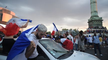 A Paris, la fête ne se limite pas aux Champs Elysées. Sur la place de la Bastille, des supporters qui n'ont pas froid aux yeux font flotter leurs drapeaux. (LUCAS BARIOULET / AFP)