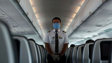 Un membre d'équipage porte un masque à bord d'un avion d'une compagnie égyptienne le 18 juin 2020. La grande majorité des personnels navigants sont en chômage technique. (MOHAMED ABD EL GHANY / X02738)