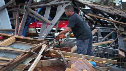 Un homme muni d'une tronçonneuse au milieu des décombres après le passage de l'ouragan Laura, à Lake Charles, en Louisiane (Etats-Unis), le 28 août 2020. (JOE RAEDLE / GETTY IMAGES NORTH AMERICA / AFP)