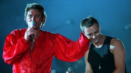 Cette fois-ci en rouge, Johnny Hallyday&nbsp;monte sur scène accompagné de son fils, David, au Parc des princes (Paris), le 18 juin 1993. (MAXPPP)