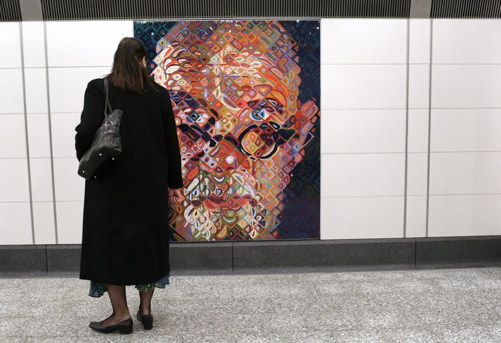 Une femme observe l'auto-portrait en mosaïque de l'artiste Chuck Close dans une station de metro new-yorkaise, le 1er janvier 2017. (YANA PASKOVA / GETTY IMAGES NORTH AMERICA)