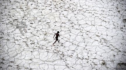 Un enfant indien joue&nbsp;dans le lit d'une rivière asséchée, le 25 octobre 2013 à Allahabad.Quelques mois plus tôt, des inondations ont&nbsp;fait plus de 5 700 victimes et d'importants dégâts dans le nord du pays. (SANJAY KANOJIA / AFP)