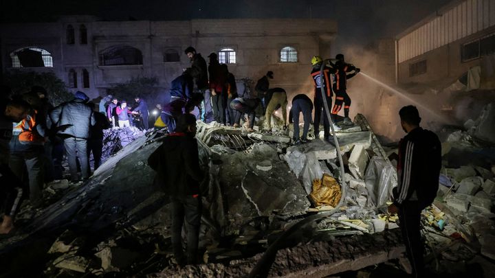 Des pompiers et des civils tentent de trouver des survivants dans les décombres d'un immeuble, à Rafah, dans la bande de Gaza, le 18 décembre 2023. (MOHAMMED ABED / AFP)