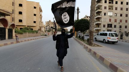 Un membre de l'Etat islamique brandit un drapeau de l'organisation, le 29 juin 2014 &agrave; Racca (Syrie). (REUTERS)