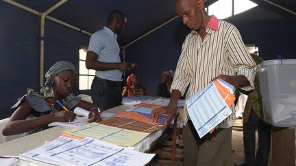 Un homme choisit des bulletins pour voter aux élections municipales et départementales du 29&nbsp;juin 2014 dans un bureau de vote à Dakar, la capitale du Sénégal. Les prochaines élections locales auront lieu le 23 janvier 2022. (SEYLLOU / AFP)