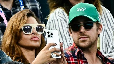 L'actrice américaine Eva Mendes (à gauche) et son compagnon l'acteur canadien Ryan Gosling (à droite) assistent à la finale des barres asymétriques féminines de gymnastique artistique lors des Jeux olympiques de Paris 2024 dans les tribunes de l'Arena Bercy, à Paris, le 4 août 2024. (LOIC VENANCE / AFP)