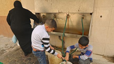 De jeunes palestiniens remplissent des bidons d'eau à un réservoir public à Gaza, dimanche 22 mars 2021. L'enclave palestinienne manque d'eau. (MOHAMMED ABED / AFP)