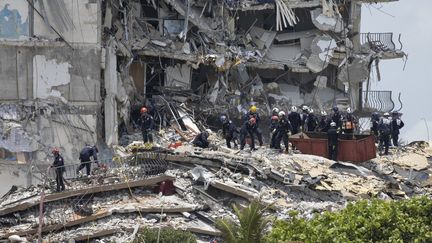 Des membres de l'équipe de sauvetage urbain recherchent d'éventuels survivants dans l'immeuble partiellement effondré, le 26 juin 2021 à Surfside, en Floride (Etats-Unis). (JOE RAEDLE / GETTY IMAGES NORTH AMERICA / AFP)