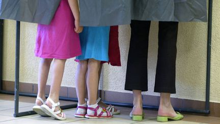 Des fillettes et leur m&egrave;re dans un isoloir lors du premier tour de l'&eacute;lection pr&eacute;sidentielle, le 22 avril 2007 &agrave; Chanonat (Puy-de-D&ocirc;me). (THIERRY ZOCCOLAN / AFP)