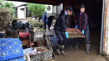 Des habitants enlèvent de la boue de leur maison inondée après le passage du typhon Hagibis, le 15 octobre 2019. (KAZUHIRO NOGI / AFP)