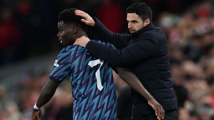 Le milieu anglais d'Arsenal Bukayo Saka avec son coach, l'Espagnol Mikel Arteta (PAUL ELLIS / AFP)