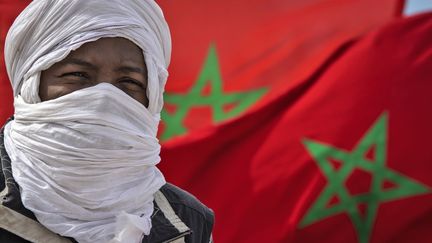 Un&nbsp;homme avec un drapeau marocain près de la frontière mauritanienne, à Guerguerat, au Sahara occidental, le 26 novembre 2020. (FADEL SENNA / AFP)