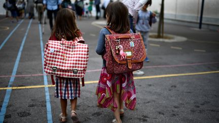 Des enfants entrent dans une cour d'école à Paris pour la rentrée scolaire, le 2 septembre 2019. (MARTIN BUREAU / AFP)